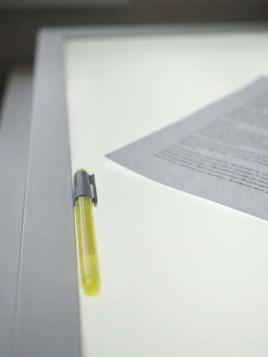Light table edge with a yellow highlighter beside a printed sheet corner.